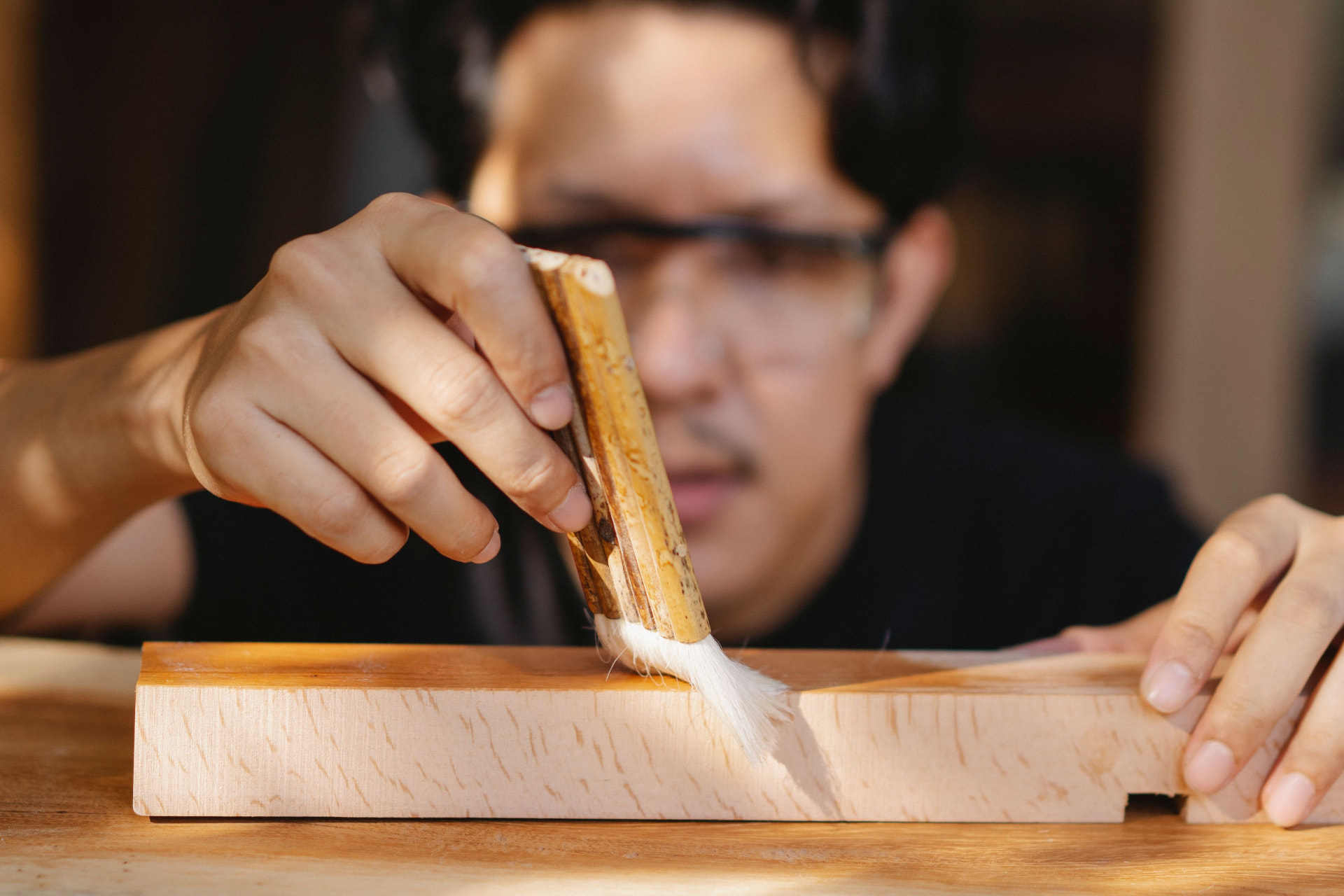 Handwerker, der mit einem Pinsel über ein Stück Holz streicht